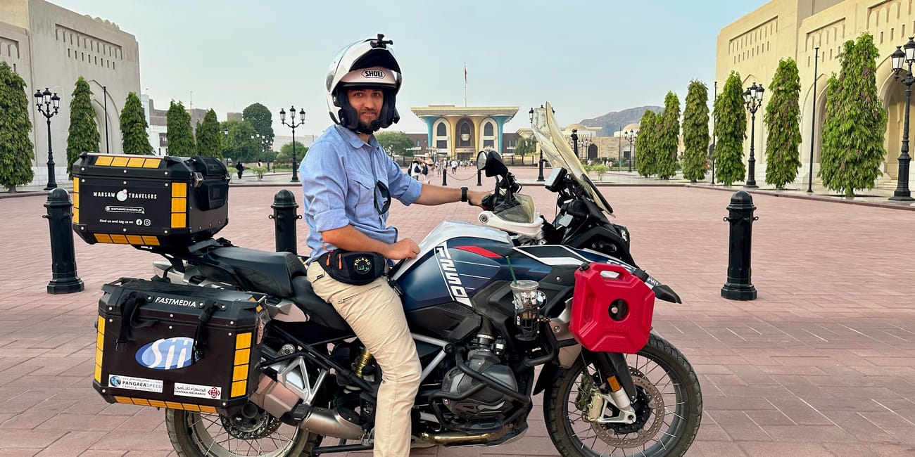 Mężczyzna na motocyklu podróżnym przed pałacem al alam w maskacie w omanie.