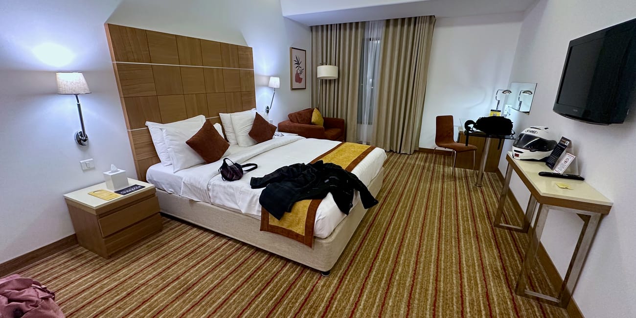 Nasz nocleg w maskacie w omanie – nowoczesny pokój hotelowy z dużym łóżkiem, biurkiem i telewizorem