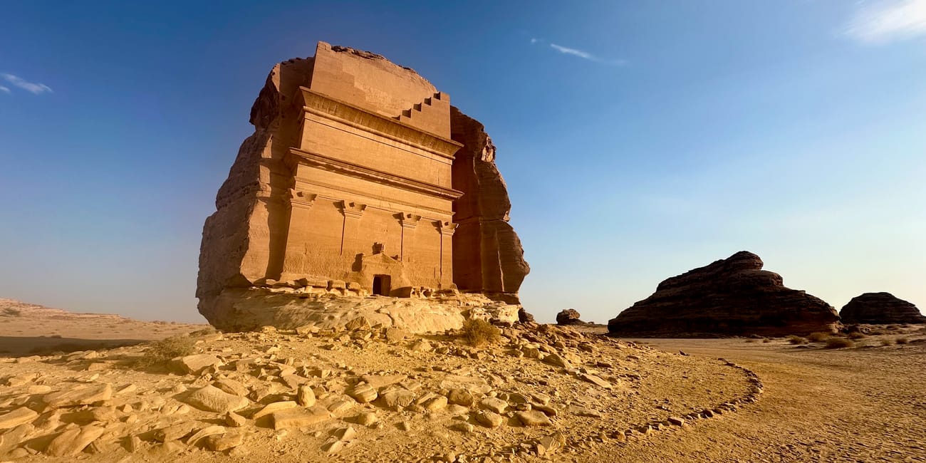 Al ula hegra in saudi arabia, ancient stone tomb monument on a rocky desert hill under a blue sky