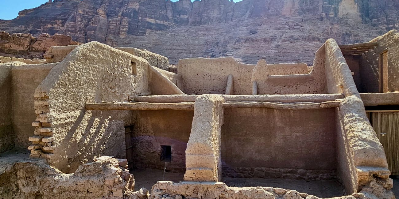 Saudi arabia, al ula old town: weathered stone ruins and courtyards beneath rugged desert cliffs