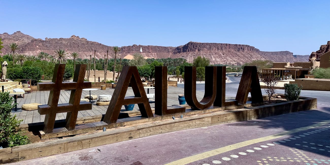 Saudi arabia, al ula old town courtyard with large wooden letters a u a u and desert cliffs in the background
