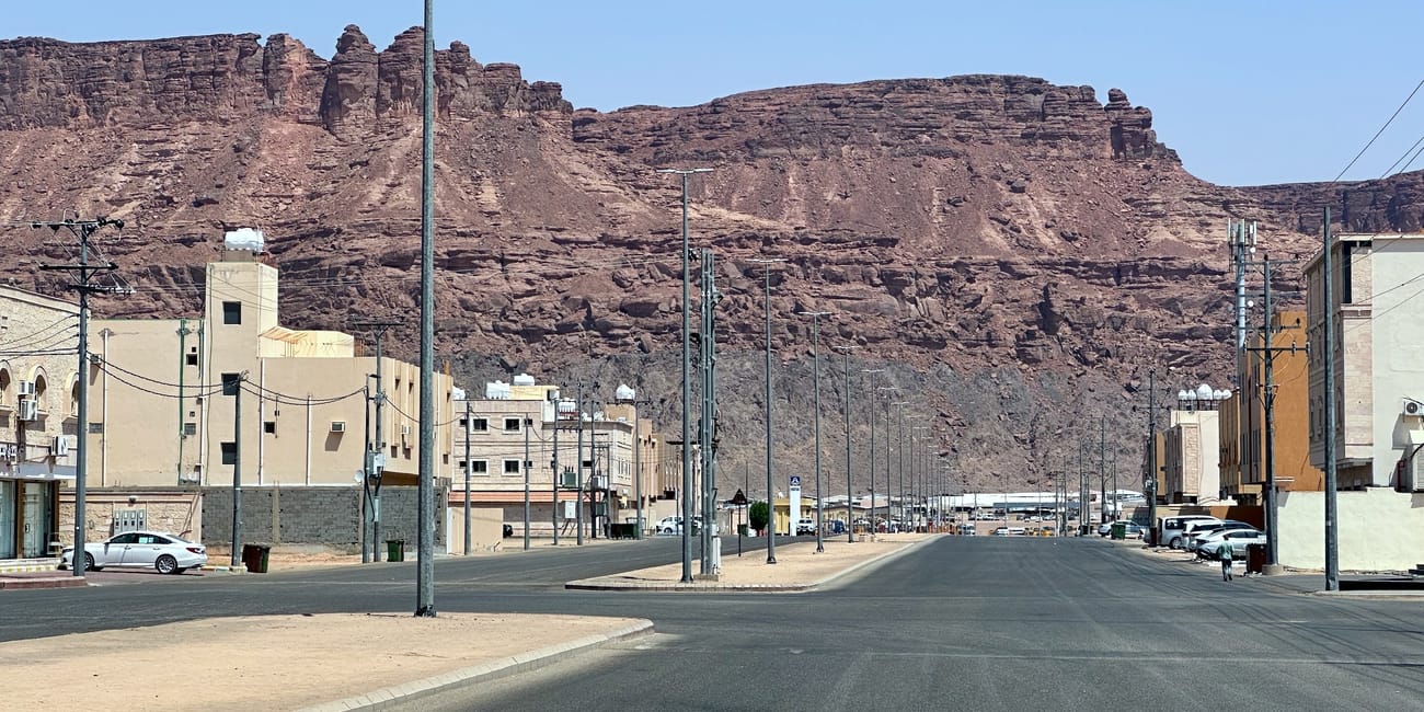 Saudi arabia, al ula road in city with street buildings and rocky mountains backdrop
