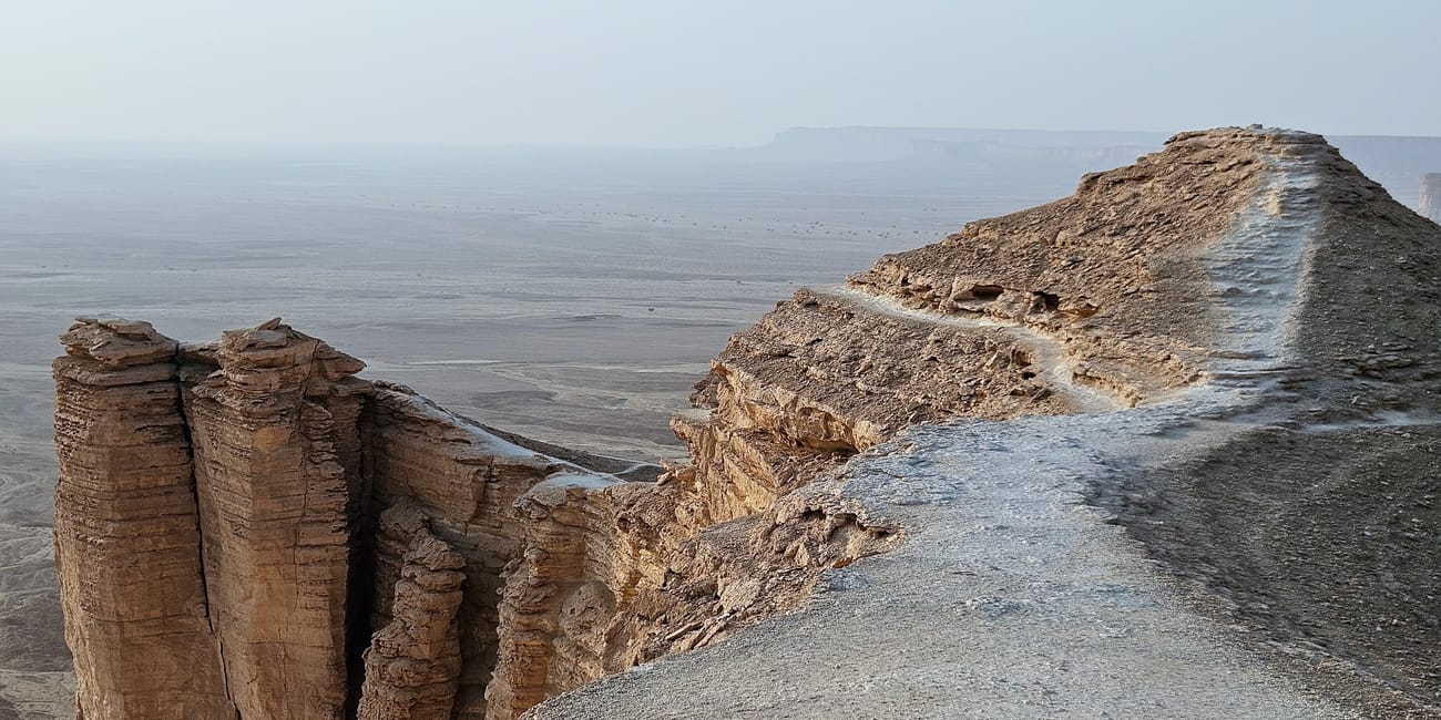 Edge of the world w arabii saudyjskiej – skalisty klif nad rozległą pustynną równiną.