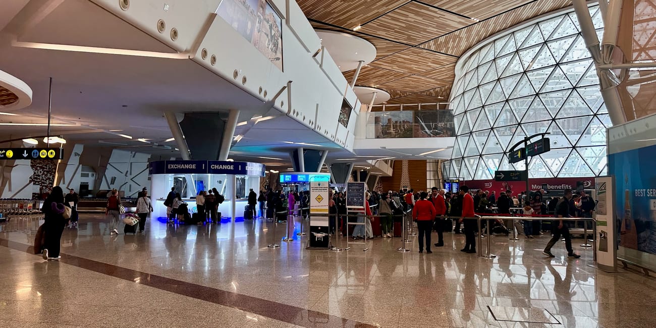 Marrakech airport departure hall with ceiling lights, check-in counters, and travelers waiting.