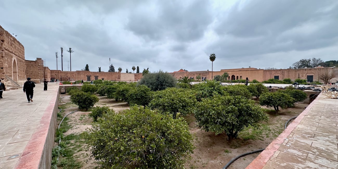 Badi palace in marrakesz, morocco, with landscaped gardens and historic stone walls under an overcast sky