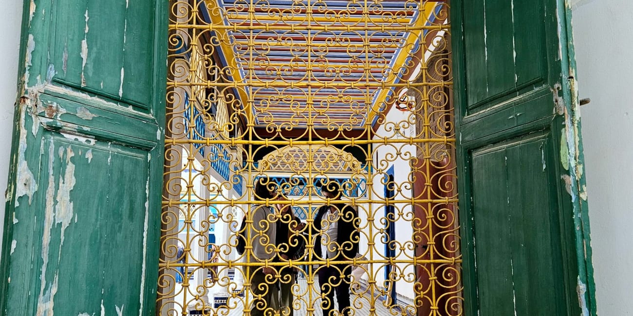 Bahia palace, marrakesz: ornate golden blue iron gate framed by weathered green doors