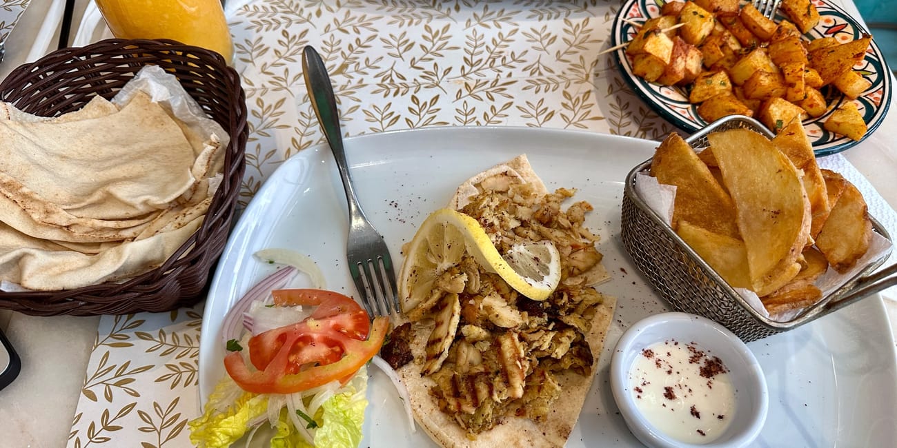 Morocco, marrakech foods: platter of moroccan flatbread with roasted potatoes, fries, salad, and dipping sauce.