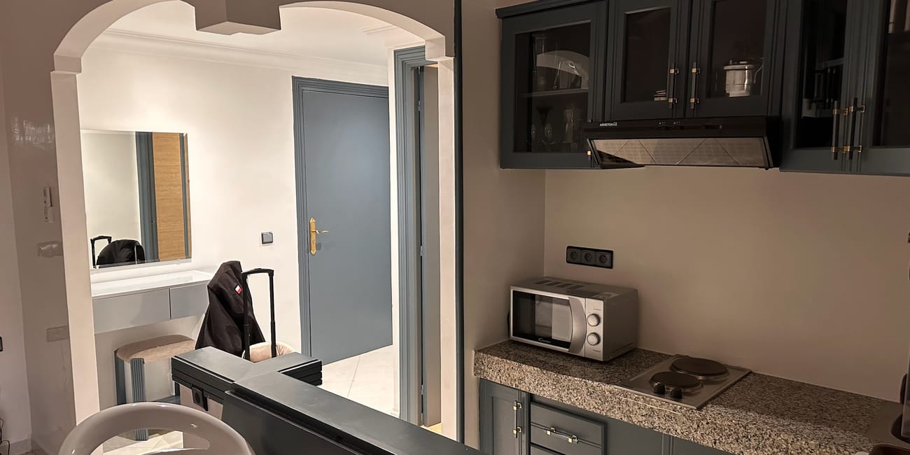 Morocco, marrakech hotel kitchenette with dark cabinetry, microwave, and an arched doorway