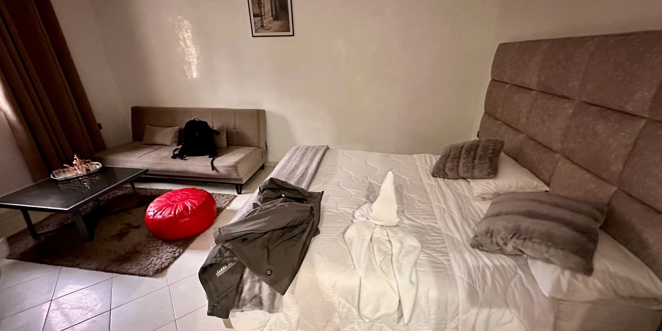 Marrakech hotel double bedroom with neatly made beds, pillows, a coffee table, and a red floor cushion