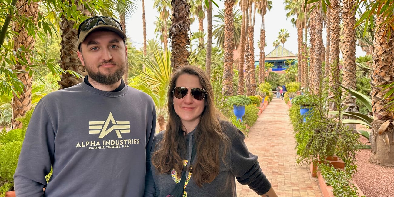 Couple posing at jardin majorelle in marrakech, morocco, with palm trees and lush garden pathways behind them