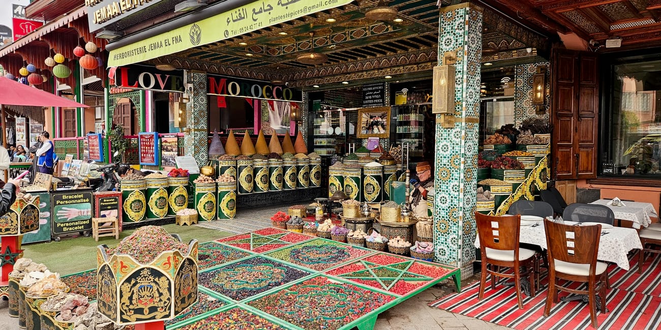 Jemaa el-fnaa in marrakech, morocco market stall with colorful woven goods, brass pots, and mosaic columns