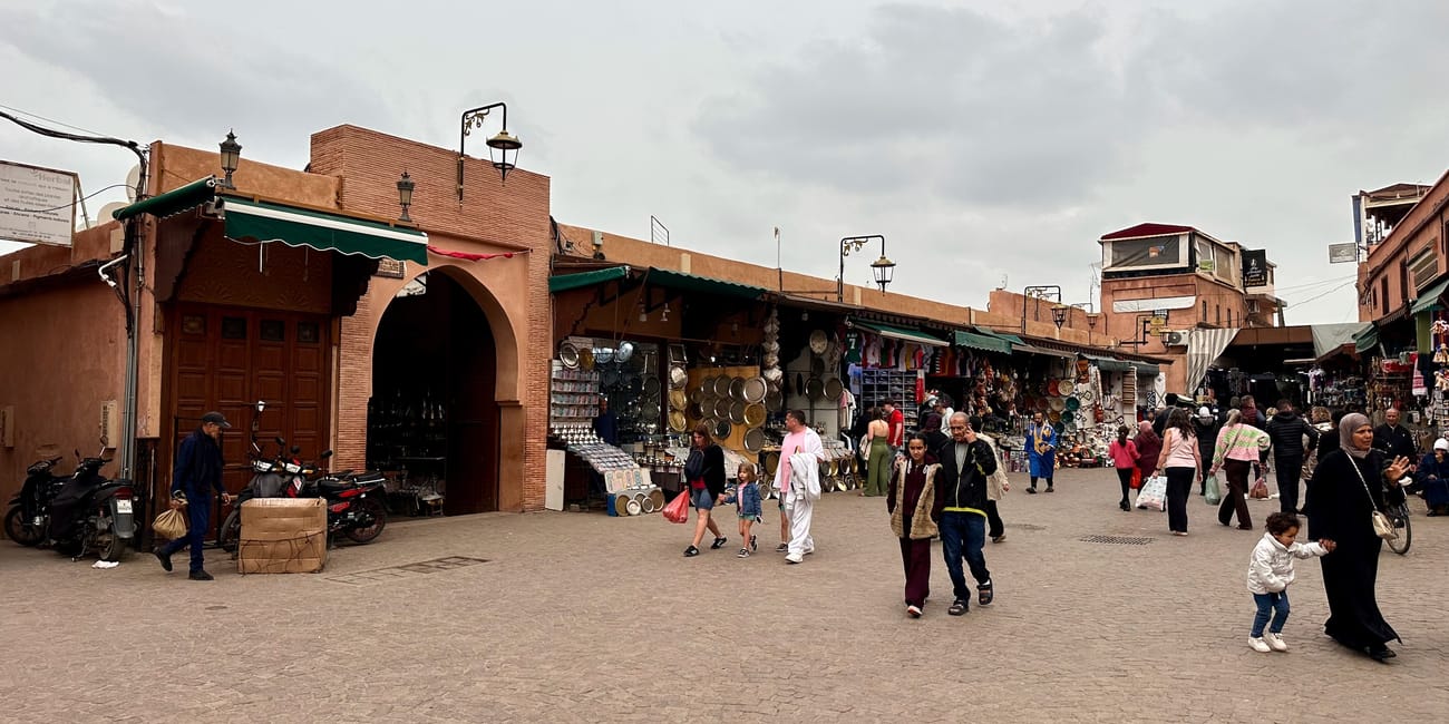 Jemaa el-fnaa in marrakesh, morocco, a busy square market with colorful stalls and archways under cloudy skies