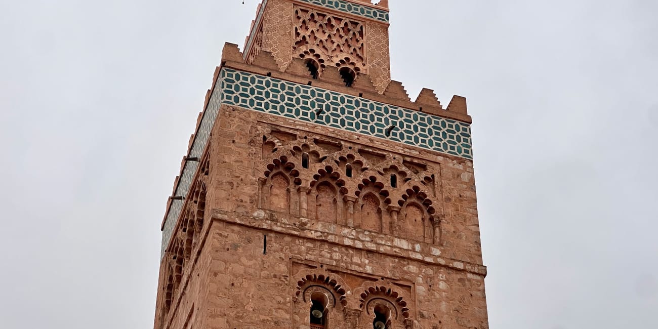 Koutoubia mosque in marrakesh, morocco, with ornate stonework and a minaret against a cloudy sky