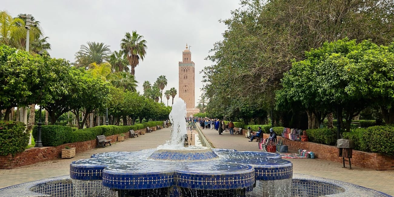 Lalla hassan park in marrakesh, morocco, with a tiled fountain and palm-lined gardens under cloudy skies