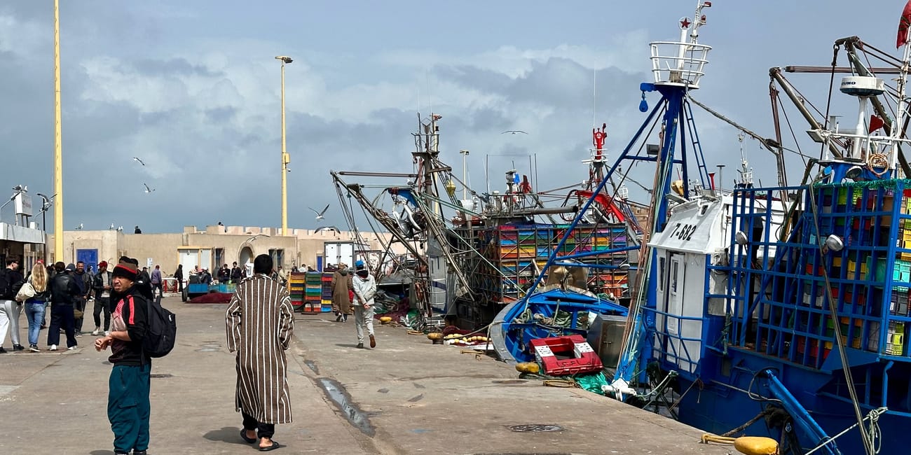 Essaouira, maroko: port z niebieskim kutrem i latarniami morskimi na nabrzeżu w słoneczny dzień