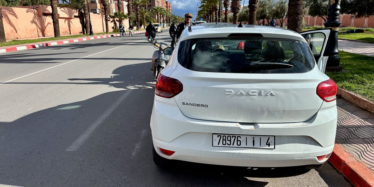 Wypadek drogowy z udziałem skutera w marrakeszu, przy białym aucie dacia sandero na palmowej ulicy
