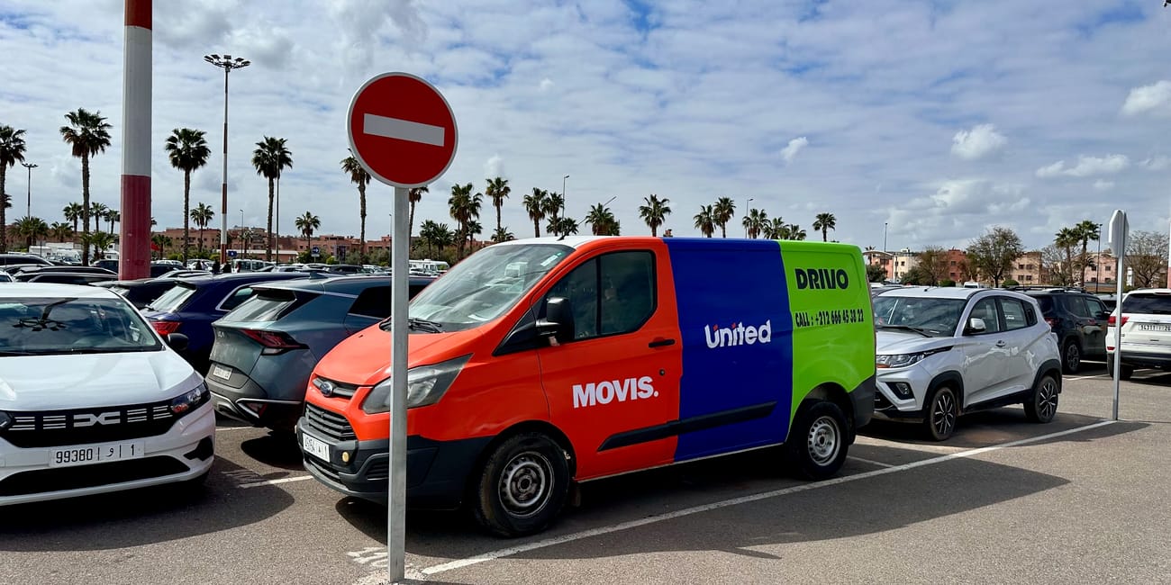 Parking w marrakeszu z kolorowym vanem wypożyczalni i znakiem zakazu wjazdu