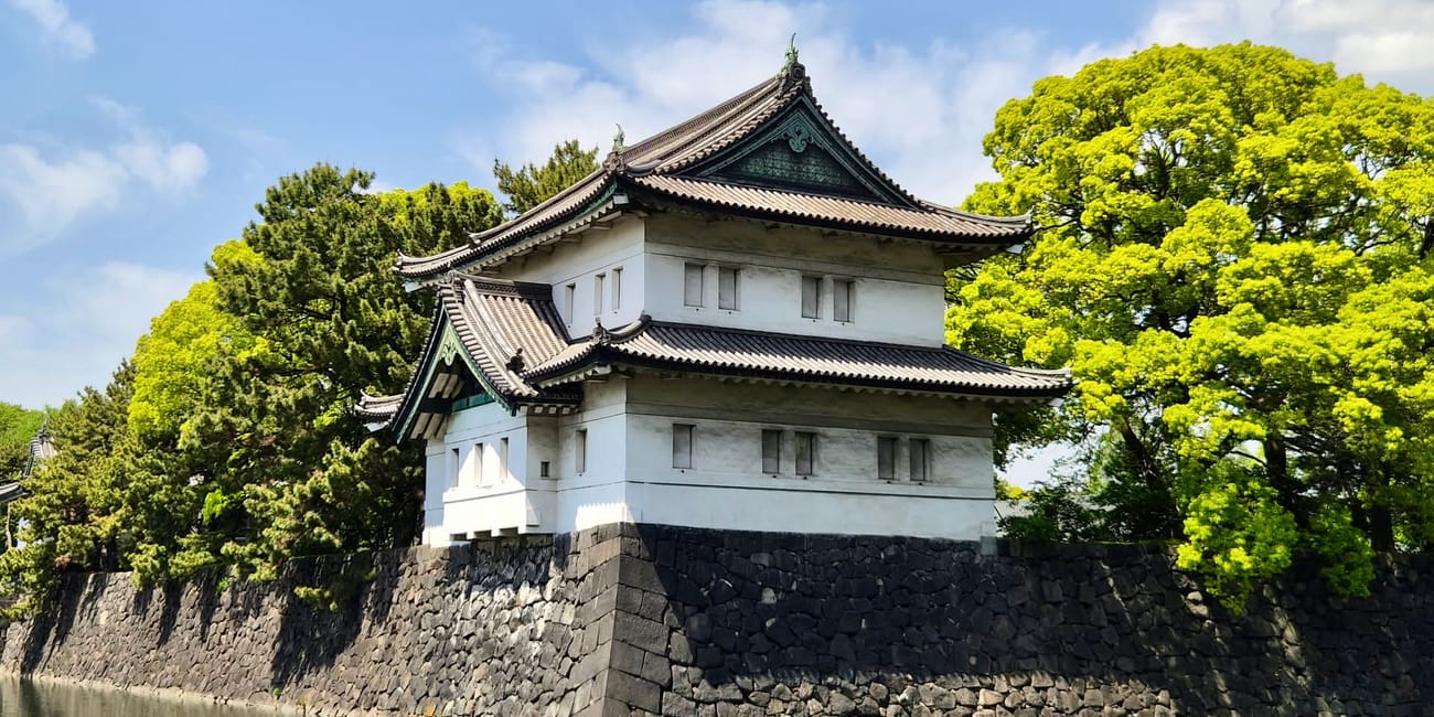Chidorigafuchi w tokio: biały budynek na kamiennym wale nad wodą, otoczony zielonymi drzewami