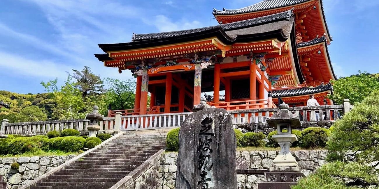 Kiyomizu-dera w kioto, czerwono-biała świątynia na wzgórzu pod błękitnym niebem