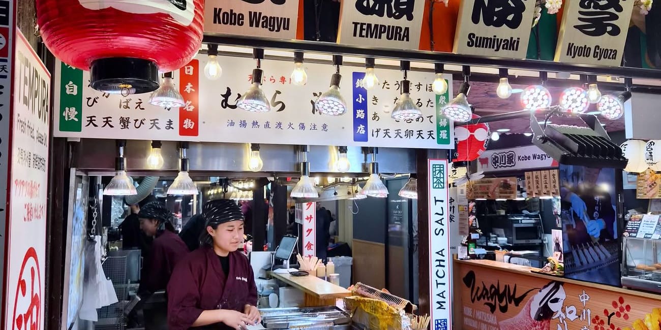 Stoisko z tempurą na nishiki market w kioto, z wystawą smażonych przekąsek i lampionami