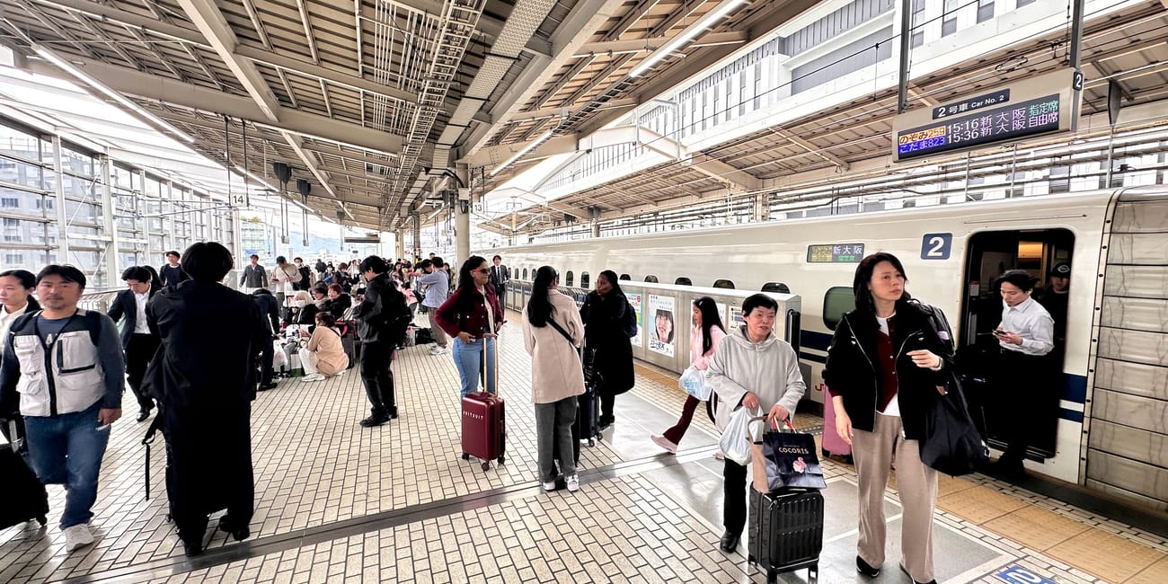 Stacja kolejowa w kioto z tłumem pasażerów przy peronie i pociągiem shinkansen