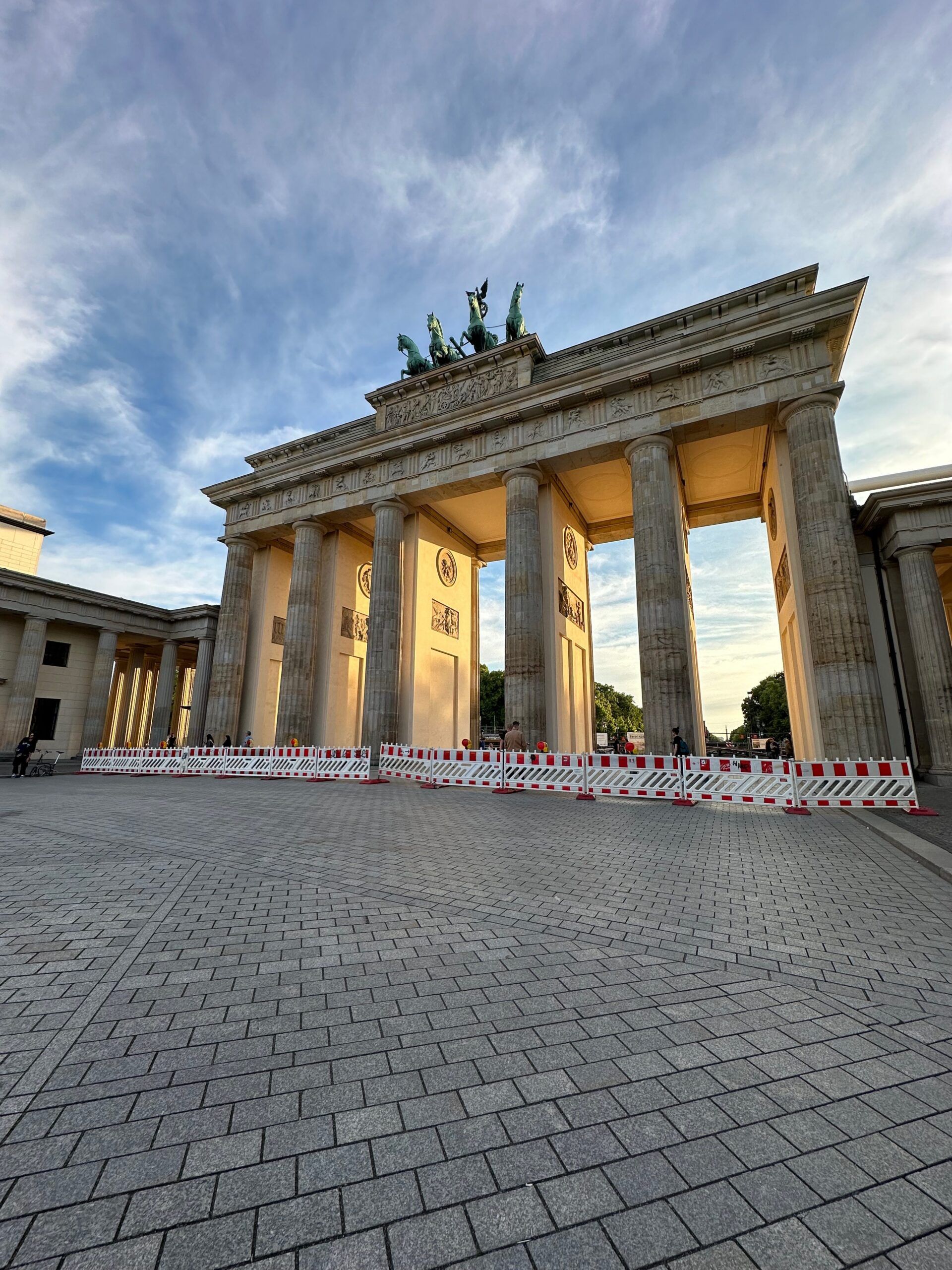 Brama brandenburska w berlinie o zachodzie słońca, z czerwono-białymi barierkami przed wejściem