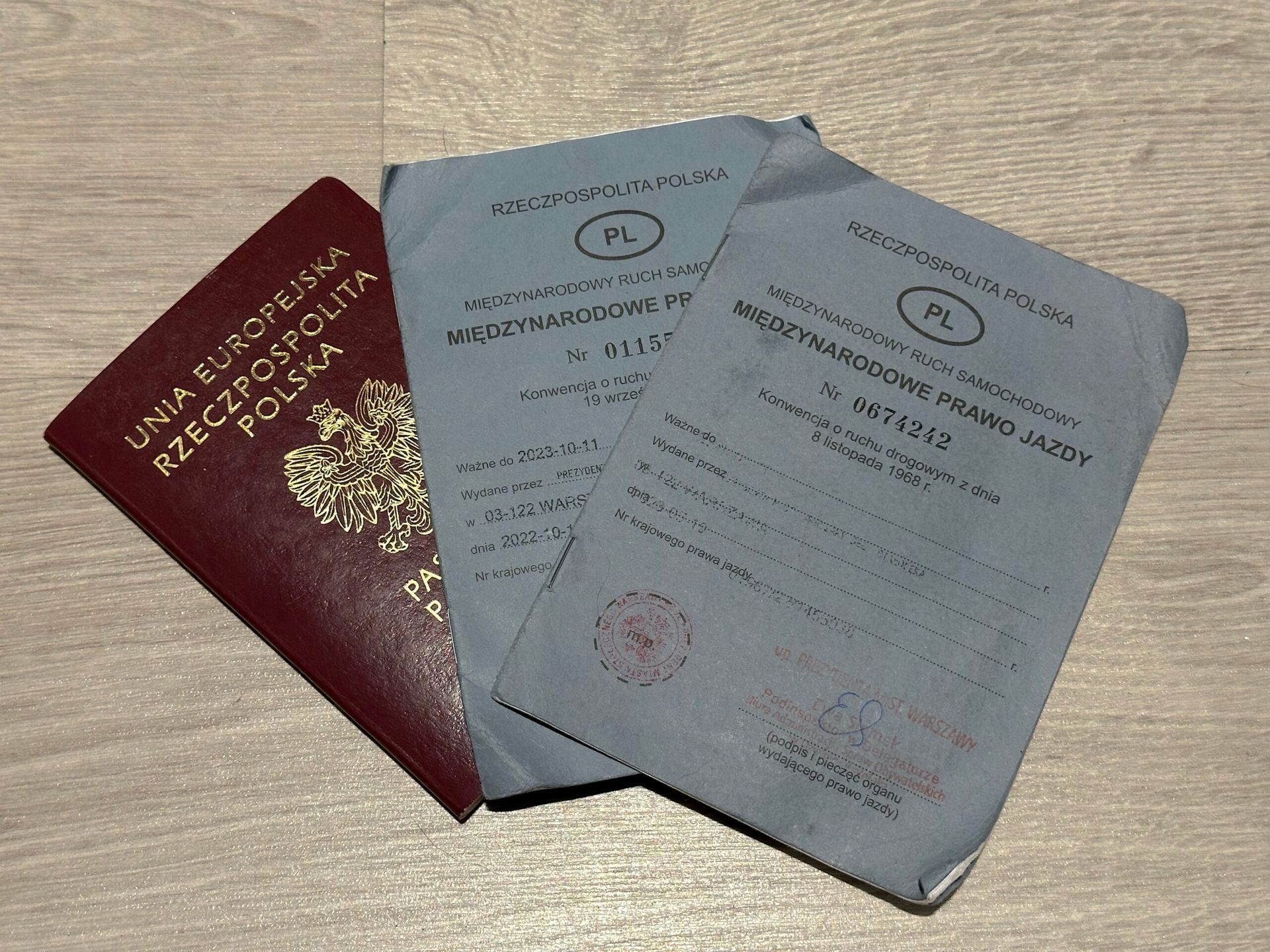Polski paszport i dwa międzynarodowe prawa jazdy na drewnianym stole