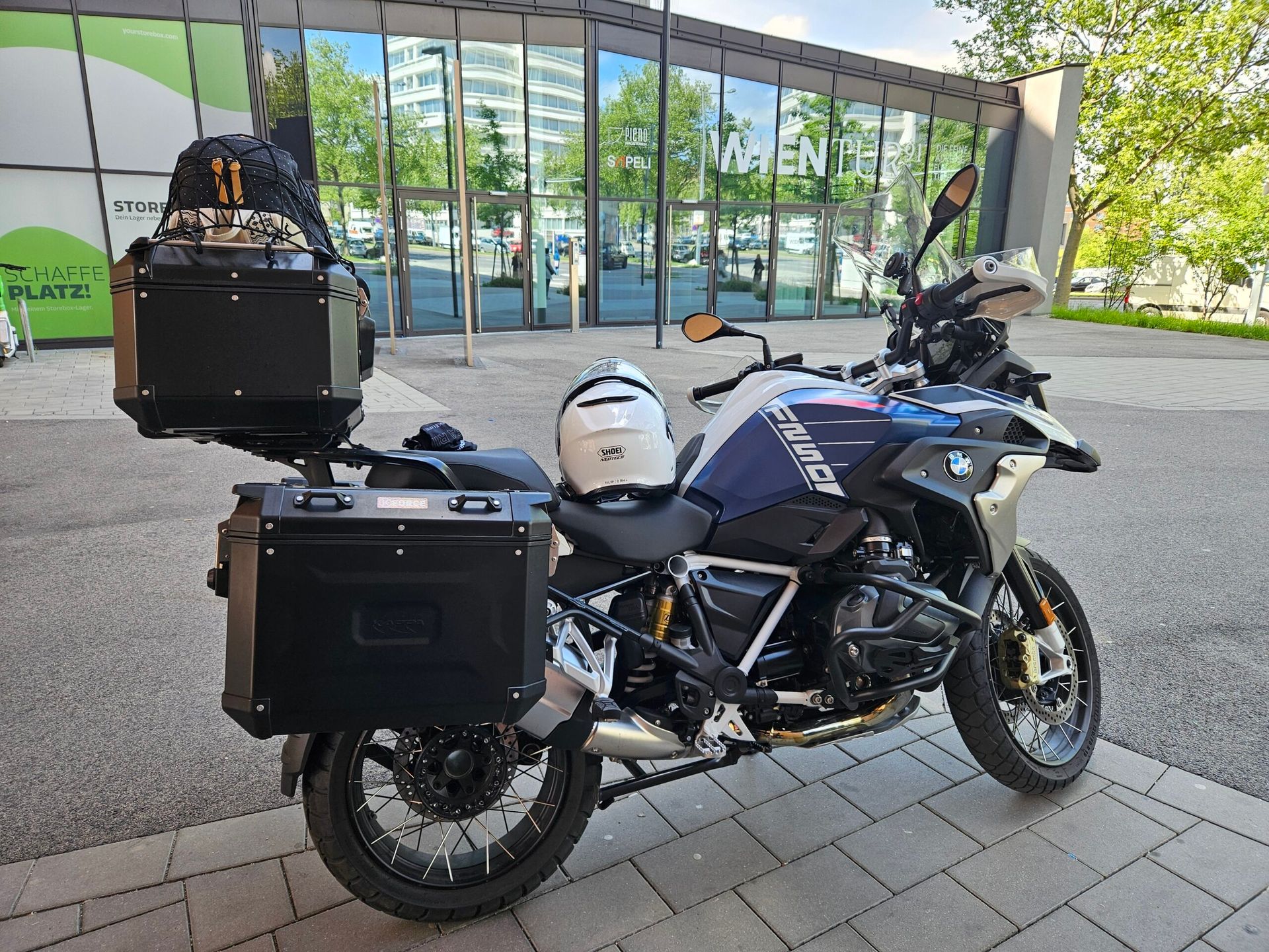Motocykl bmw z kuframi zaparkowany przy nowoczesnym budynku w bratysławie.