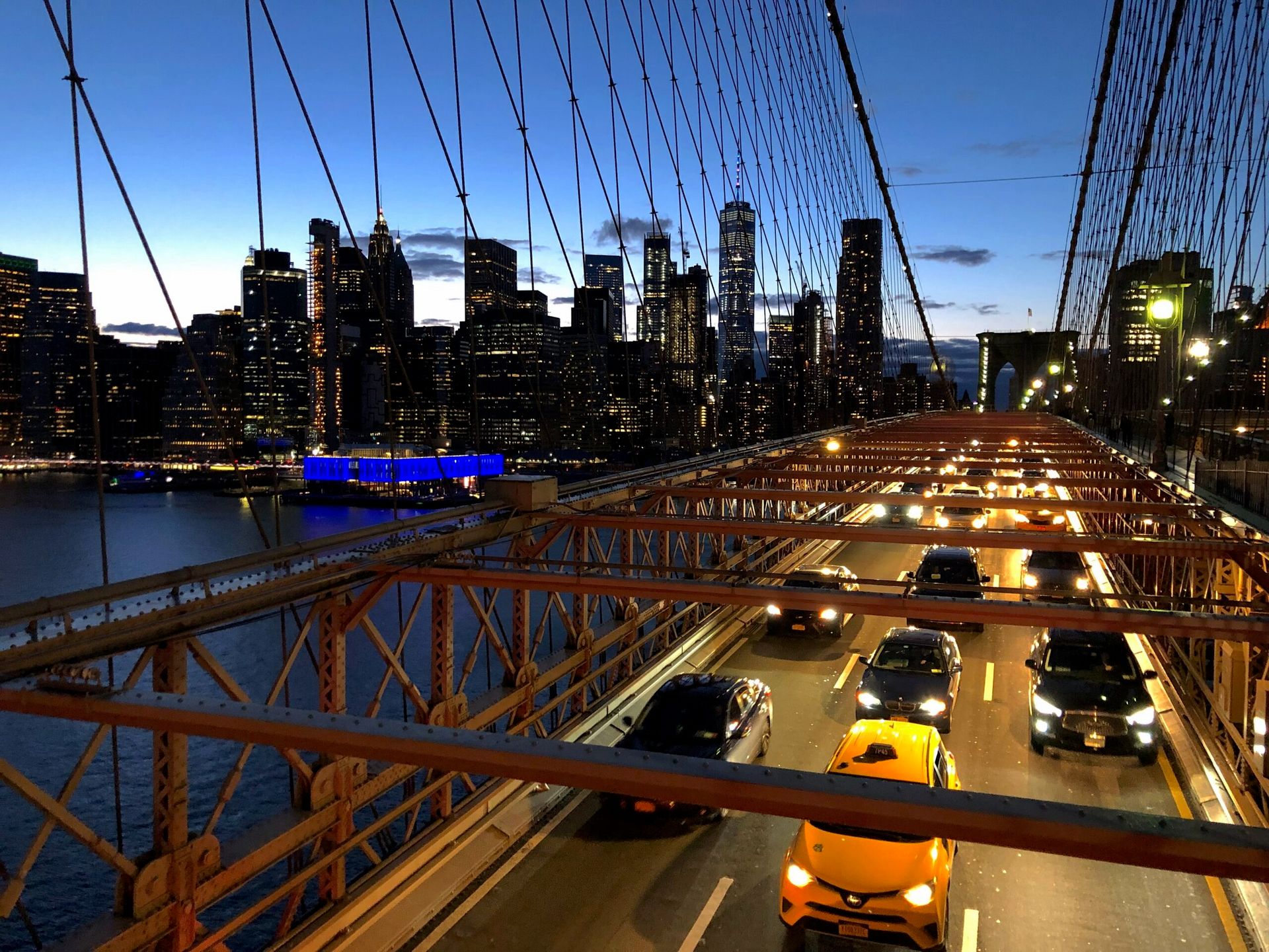 Most brookliński w nowym jorku z ruchem samochodowym i panoramą manhattan o zmierzchu