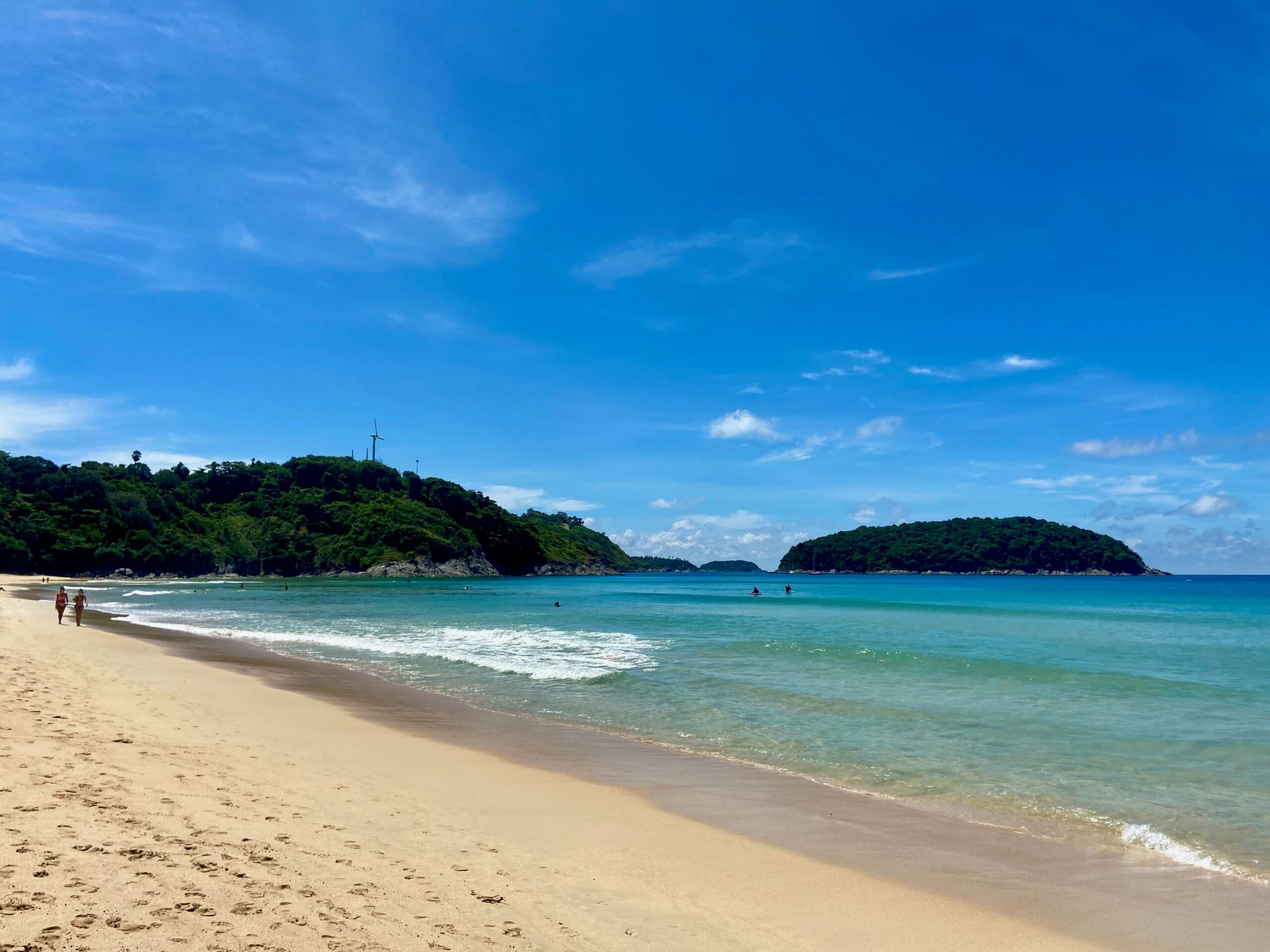 Plaża w phuket w tajlandii z turkusową wodą, żółtym piaskiem i zielonymi wzgórzami w tle