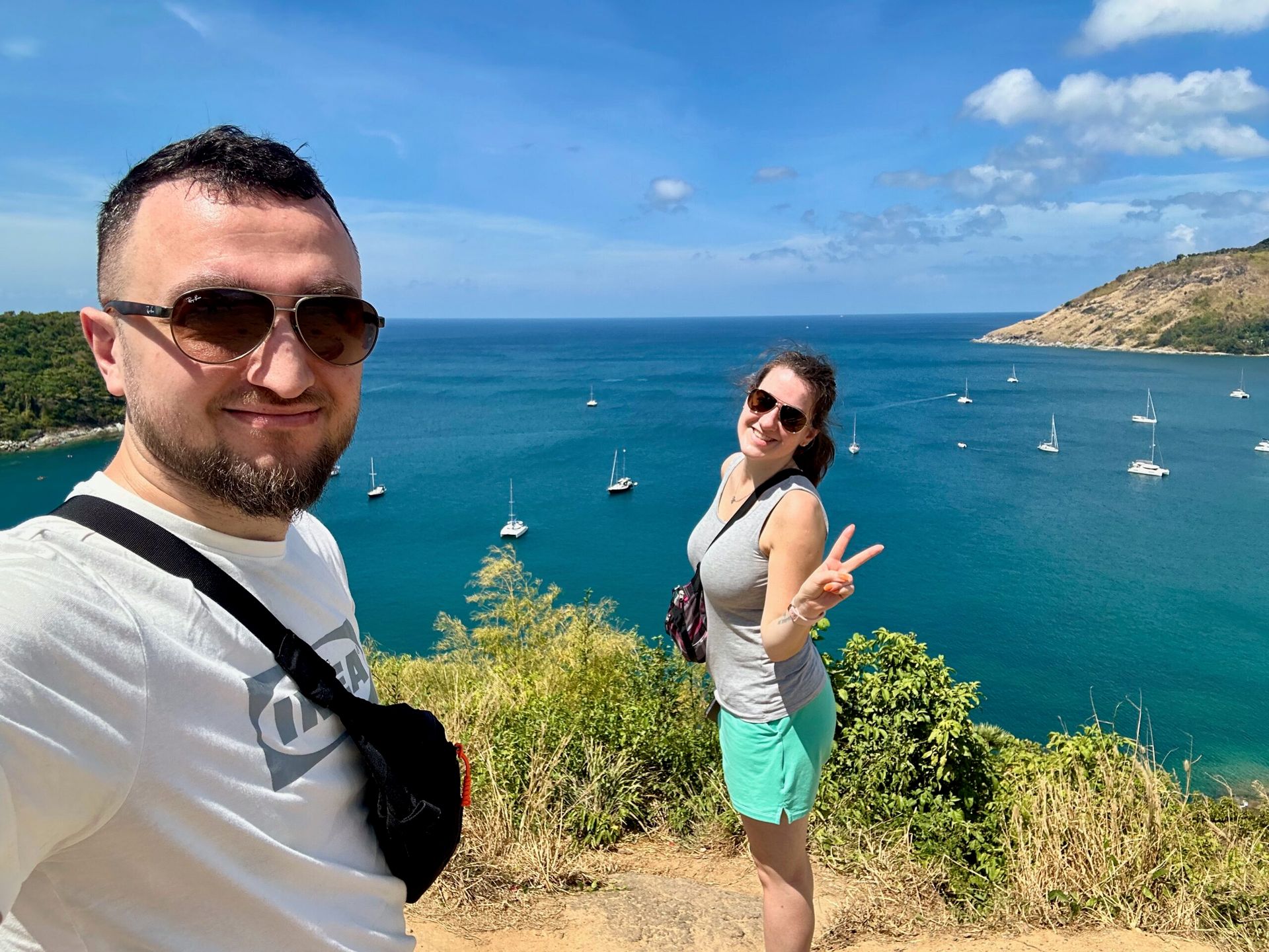 Para zakochanych robi selfie na klifie z widokiem na zatokę phuket z żaglówkami.