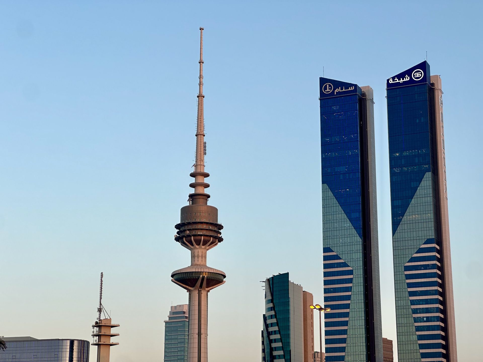 Widok zabudowy w kuwait city z wieżą telekomunikacyjną i nowoczesnymi wieżowcami.