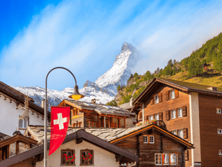 Zermatt w szwajcarii z matterhornem w tle i szwajcarską flagą między górskimi domami