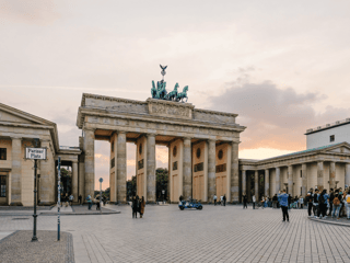 Brama brandenburska na pariser platz w berlinie o zachodzie słońca, z turystami na placu.