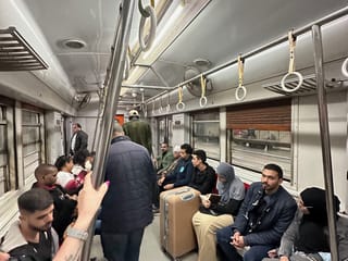 Passengers inside an egypt metro car, with seated riders and a suitcase in the aisle