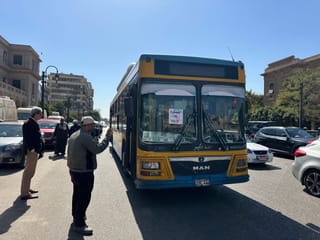 Public bus on a busy street in egypt, with people hailing it.