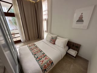 Bedroom in cairo livingville nine, egypt, with a bed, patterned runner, and curtains by a window.