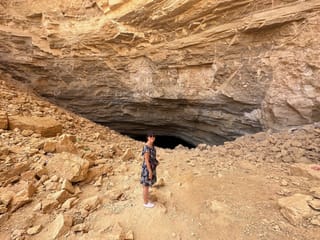 Riyadh heet cave in saudi arabia, with a person standing at the cave entrance.