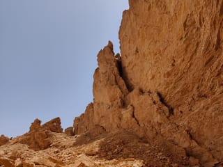 Heet cave w rijadzie, skaliste ściany i kamieniste zbocze pod bezchmurnym niebem.