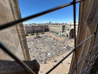 Widok na piazza del duomo w mediolanie z góry, przez kamienne okno katedry.