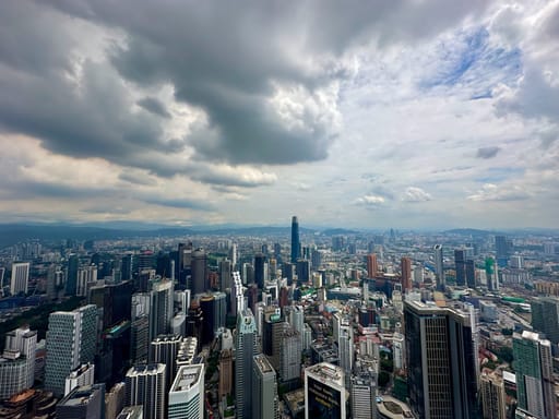 Panorama kuala lumpur z wieżowcami pod dramatycznym, zachmurzonym niebem.
