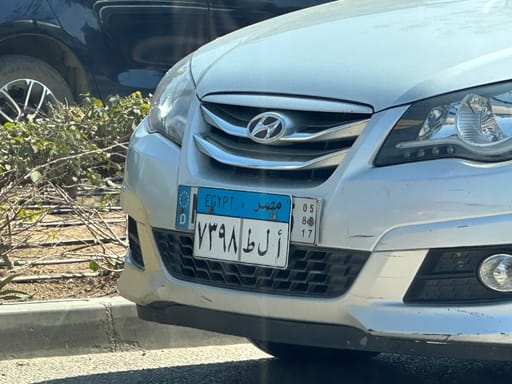 Przód samochodu z egipską tablicą rejestracyjną na ulicy.