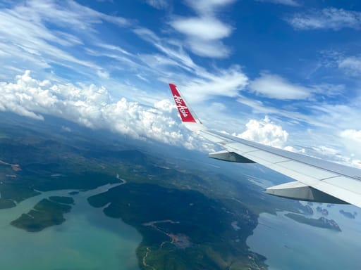 Widok z okna samolotu airasia nad wybrzeżem z wyspami i chmurami