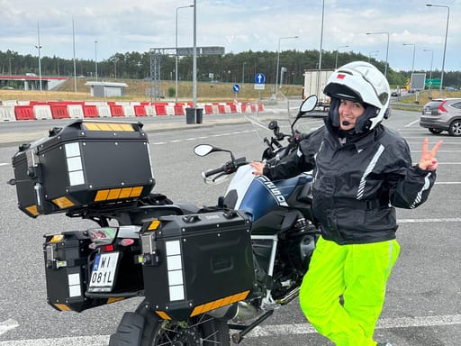 Kobieta w kasku stoi przy motocyklu turystycznym na parkingu w niemczech.