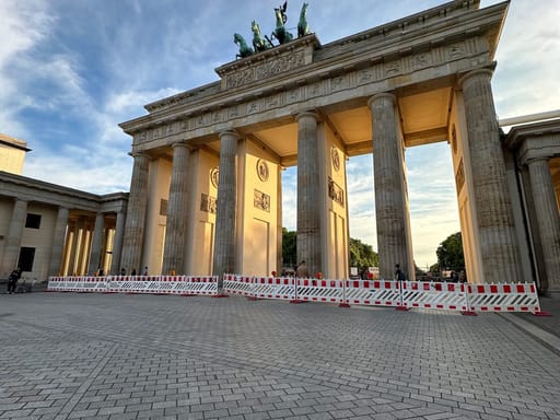Brama brandenburska w berlinie o zachodzie słońca, z czerwono-białymi barierkami przed wejściem