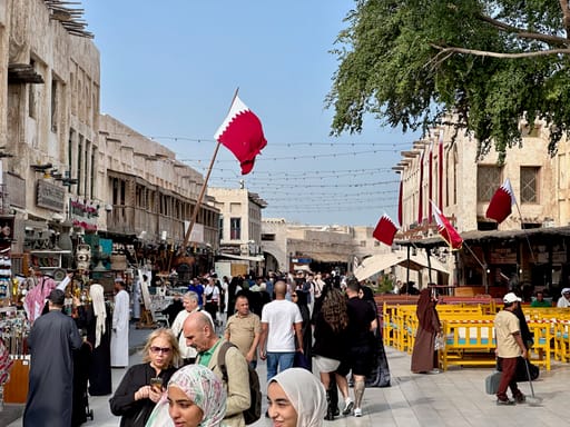 Souk waqif w dosze z tłumem spacerujących i flagami kataru