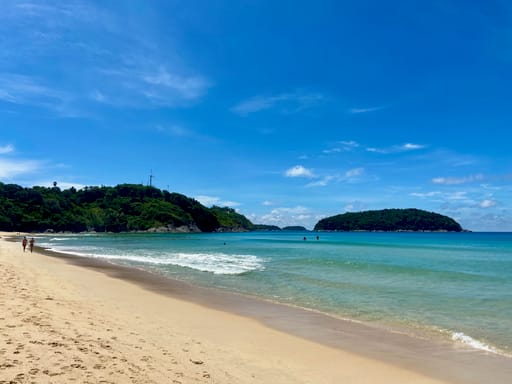 Plaża w phuket w tajlandii z turkusową wodą, żółtym piaskiem i zielonymi wzgórzami w tle