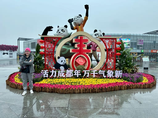 Dekoracyjna instalacja z pandami w chengdu, otoczona kwiatami i chińskimi lampionami.