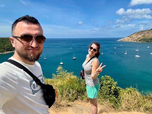 Para zakochanych robi selfie na klifie z widokiem na zatokę phuket z żaglówkami.