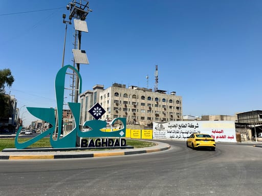 Znak bagdad z napisem baghdad na rondzie w mieście, z żółtym samochodem w tle